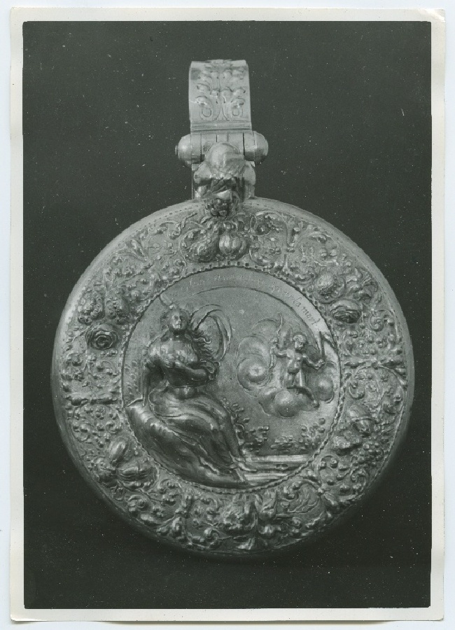 Kann, kaas kaunistatud kõrgreljeefse ornamendiga, keskel istuv naine ja Amor pilvedes, ääres lillemotiivid.