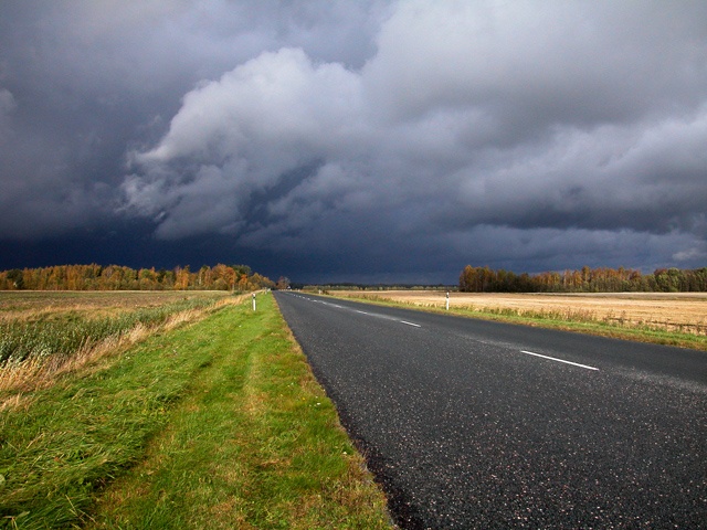 In autumn paints landscape, dark clouds and wet asphalt near Audru.