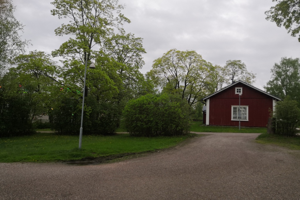 Latokartanonkaari 3. Näkymä Viikin Latokartanosta Viikintien suunnalta nykyisen Viikinkaaren suuntaan. Oikealla tien laidassa punainen puurakenteinen asuinrakennus Viikin koetilan työntekijöitä varten. Taustalla nostokurki Helsingin yliopiston Viikin maataloustieteellisten laitosten rakennustyömaalla nykyisellä Latokartanonkaarella. Taaempana Pihlajamäen kallioita. rephoto