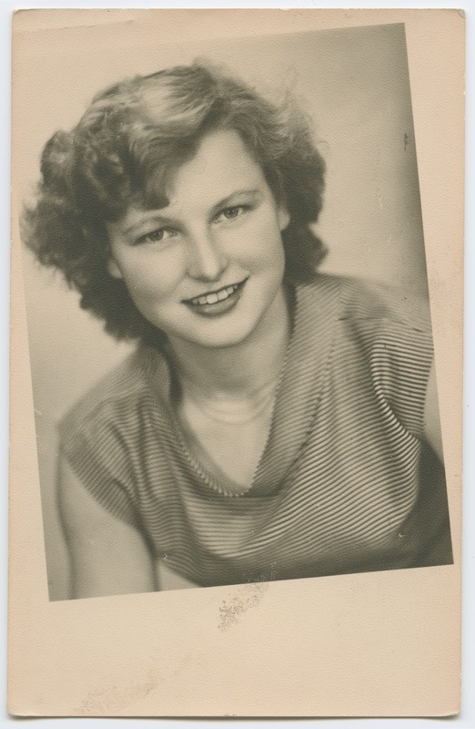 Naeratav, triibulises pluusis noor naine. Poolportree. Ateljeefoto.