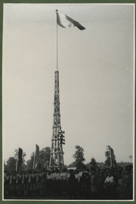 XII üldlaulupidu 28.-29. juunil 1947, Tallinnas.
12. üldlaulupeo osalejad ja pealtvaatajad Tallinna lauluväljakul. Vasakul rahvariietes naiskoori lauljad, vasakul näha pealtvaatajaid. Foto keskel masti otsas lehvimas lipp.