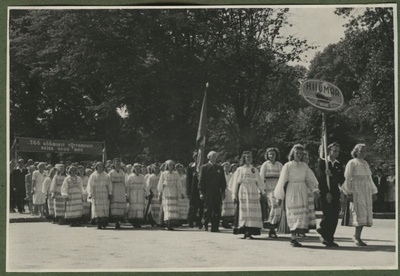 XII üldlaulupidu 28.-29. juunil 1947, Tallinnas.
Hiiumaa esindajad 12. üldlaulupeo rongkäigul. Rahvariietes hiidlased esireas kannavad Hiiumaa silti, neist tagapool kantakse lippu. Rongkäigu tagumises osas kantakse loosungit: "Töö rõõmsast tõttamisest kajab kogu maa".  duplicate photo