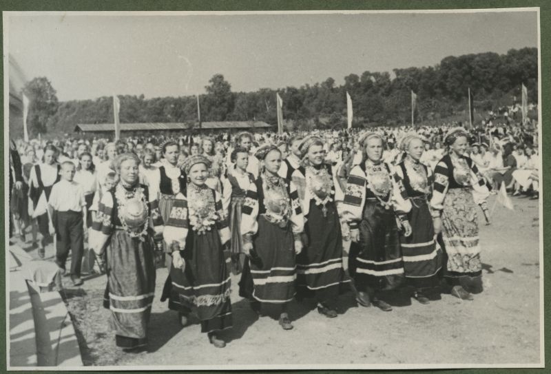 XII üldlaulupidu 28.-29. juunil 1947, Tallinnas.
12. üldlaulupeo osavõtjad rongkäigul Tallinna lauluväljakul. Eesreas Seto rahvariietes noored tüdrukud, rahvariideid ehivad suured Seto sõled. Tagaplaanil näha istuvat publikut.