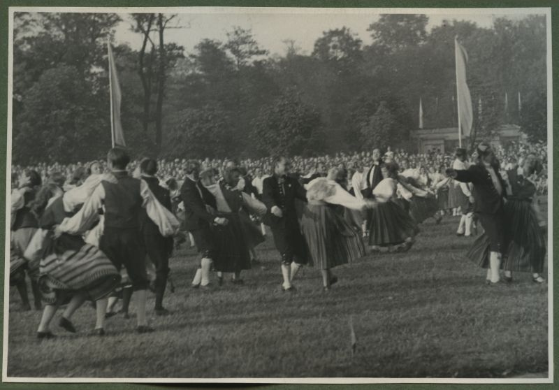 XII üldlaulupidu 28.-29. juunil 1947, Tallinnas.

Rahvariietes tantsijad rahvakunstiõhtul 12. üldlaulupeo eelõhtul Kadrioru staadionil. Segapaaridest koosnevad rahvatantsurühmad, kes on riietatud erinevatesse rahvariietesse tantsivad paarides. 
Tagaplaanil paistab tribüünil etteastet nautiv publik.