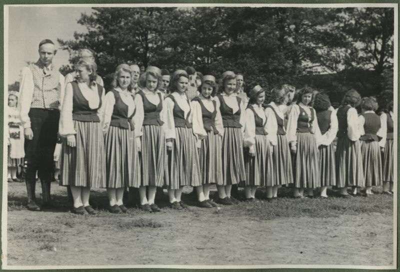 XII üldlaulupidu 28.-29. juunil 1947, Tallinnas.

Rahvarõivais rahvatantsurühm seismas rahvakunstiõhtul 12. üldlaulupeo eelõhtul Kadrioru staadionil. Tantsijad seisavad kahes reas: esimeses reas naistantsijad, tagumises meestantsijad. Taga võib seismas näha teist rahvatantsurühma.