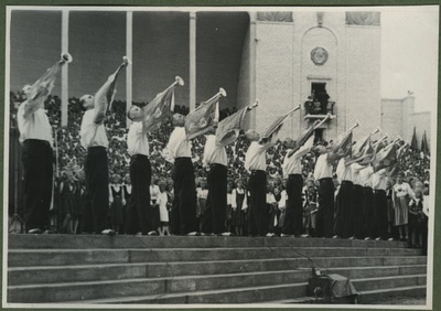 XII üldlaulupidu 28.-29. juunil 1947, Tallinnas.
12 mustadesse viigipükstesse ja valgetesse särkidesse riietatud meest puhuvad fanfaare, et kuulutada 12. üldlaulupeo algust. Kõikidel fanfaaridel on samasugused vimplid, millel peal erinevad kujutised, millest üks on kannel. Taga paistavad laulukaare alla rivistunud koorilauljad. Paistab natukene Tallinna vana laululava seina ja mõned sambad. Laululava rõdul on näha pealtvaatajaid.  duplicate photo