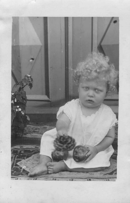 Portreefoto. Väikelaps vaibal, käes õunad