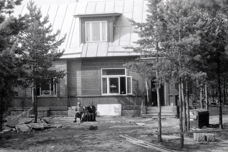 Mees ja naine poisiga maja ees istumas (Jakobson)