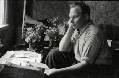 Mees ajalehega väikse laua ees istumas  similar photo