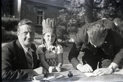 Ilutrüki trükikoja juhataja Leonhard Kahl (vasakul), laps ja mees õues laua taga kirjutamas  similar photo