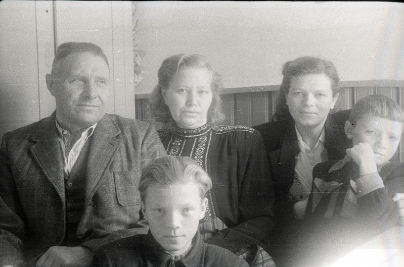 Mees kahe naise ja kahe poisiga toas istumas
