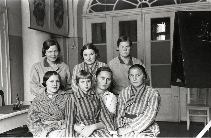 Naine med.õe riietuses viie hommikumantlites naise ja ühe tüdrukuga (7.11 I sisehaiguste kliinikus)