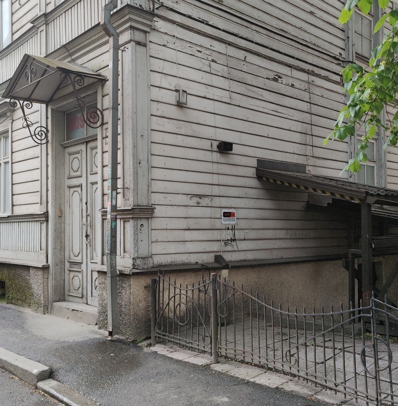Wooden house on Sakala Street. Outdoor door and squeezing. A slogan on the wall: "Come home." rephoto