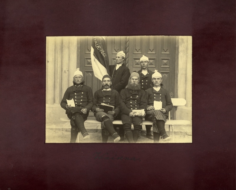 Grupipilt. Vaikna meeskoor Kullamaa kihelkonnast Haapsalu laulupeol 1896.aastal. Fotol 6 rahvariides meest koorilipuga.