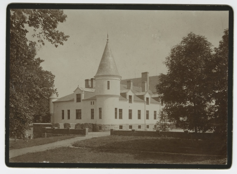 The main building of Alatskivi Manor is farther away. On the front of the grass, on the left road. Left and right trees. Lower borders from the brickstone, behind the centre of the manor building from the side.