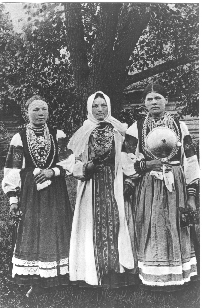 Foto. Kolm rahvarõivais  setu neidu seismas puu all XX sajandi I veerandil