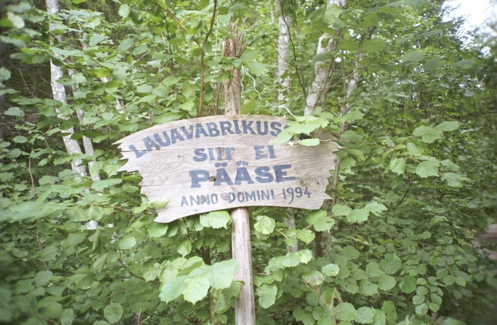 Puidust silt tekstiga "Lauavabrikusse siit ei pääse, Anno Domini 1994" Rapla-Türi maantee ääres Hiie küla ligidal