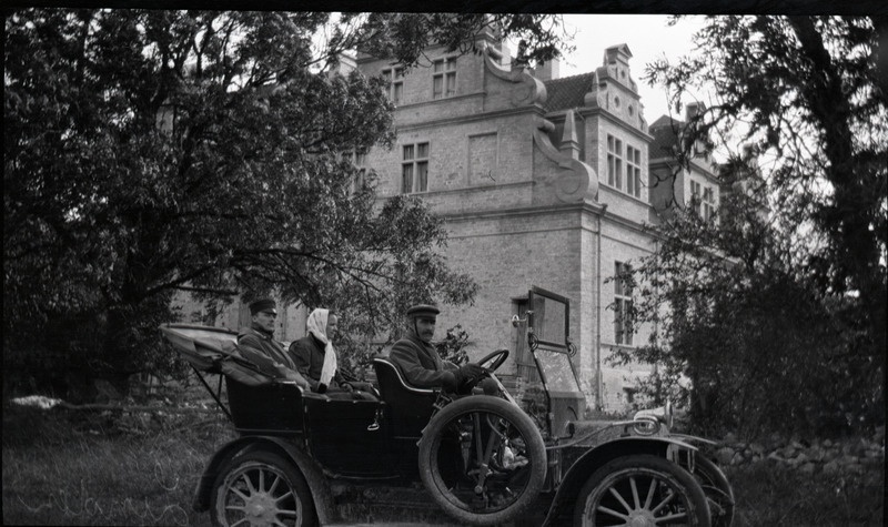 Mees, naine ja juht automobiilis. Taustal Ungru mõisa peahoone
