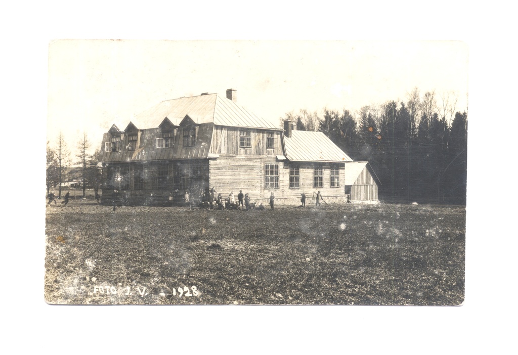 Must-valge foto vaatega puust koolihoonele, mille ees mängivad koolilapsed