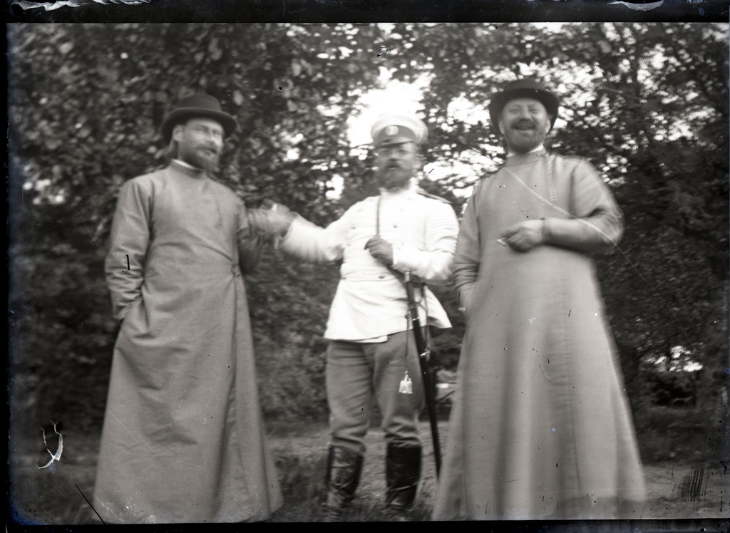 Mõõgaga ohvitser ja kaks meest aias seismas