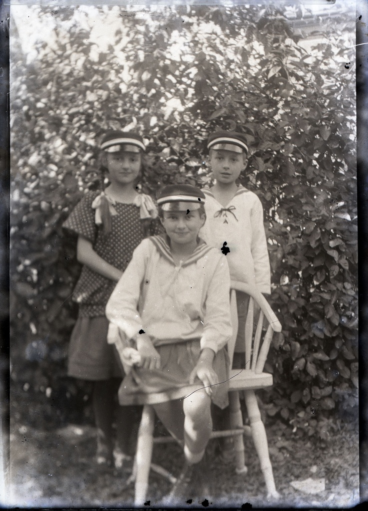 Kolm vormimütsidega koolitüdrukut aias