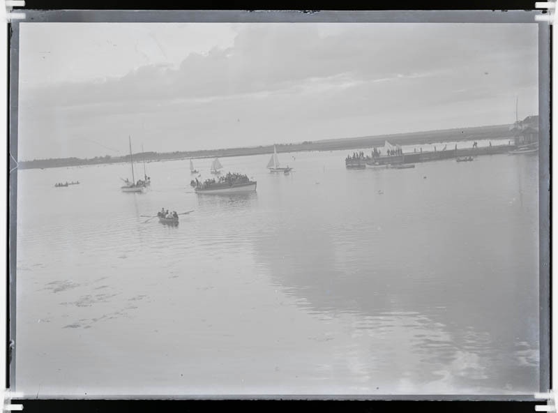 Kuressaare laht; puhkajad jahtide ja paatidega lahel. Paremal näha saksa jahtklubi sadamasild, sillal rahvas.