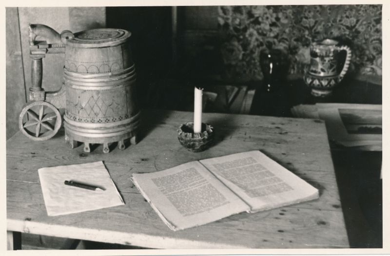 Foto. Ants Laikmaa majamuuseumi väljapanekust, 1961. Vaade magamistoas akna all olevale lauale, raamat, küünal, õllekapp.