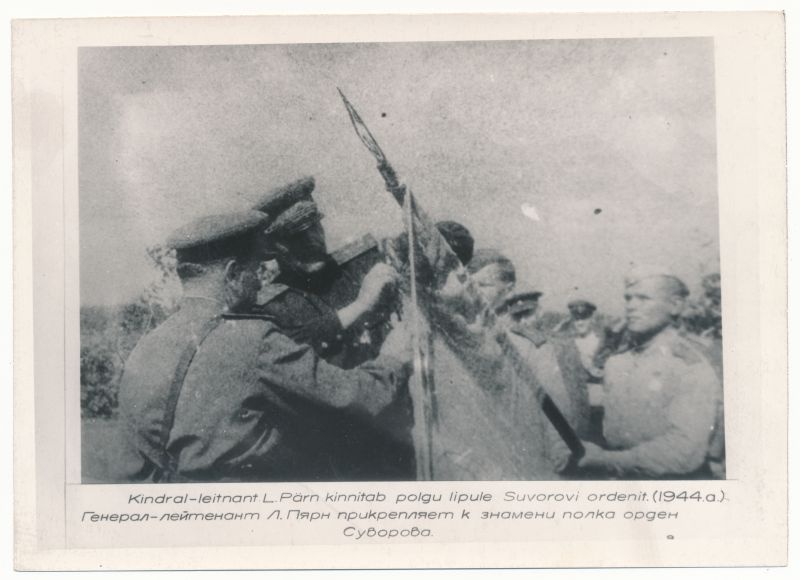 Foto. Eesti Laskurkorpuse lindral-leitnant L- Pärn kinnitab polgu lipule Suvorovi ordenit. 1944.