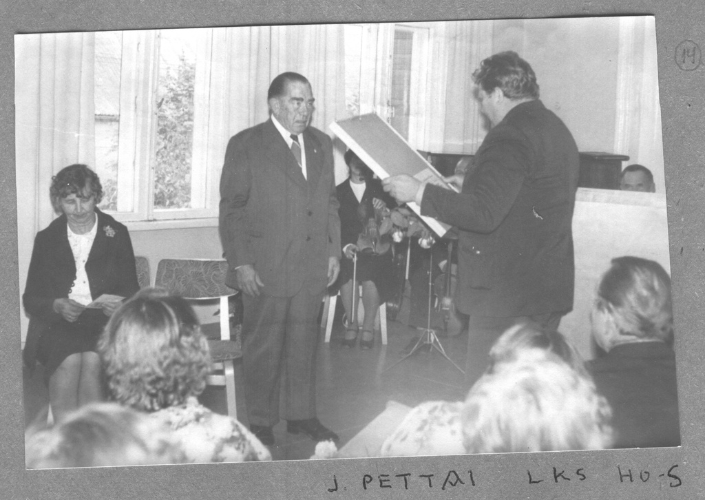 Fotoalbum. Albert Ivaski 75. sünnipäev haridusosakonna saalis 1981.a. septembris. Juubilari õnnitleb Võru Rajooni looduskaitse inspektor Jakob Pettai.