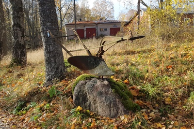 Vanha ruosteinen aura kivellä Vallisaaressa. Taustalla avautuu näkymä paloaseman pihapiiriin. Vasemmalla näkyvä punaovinen rakennus on palokalustovaja, jossa säilytettiin aikanaan T-mallista Fordia, kuorma-autoa ja hevosvetoisia kärryjä. Sitä vastapäätä oikealla näkyy puusepänverstas. rephoto