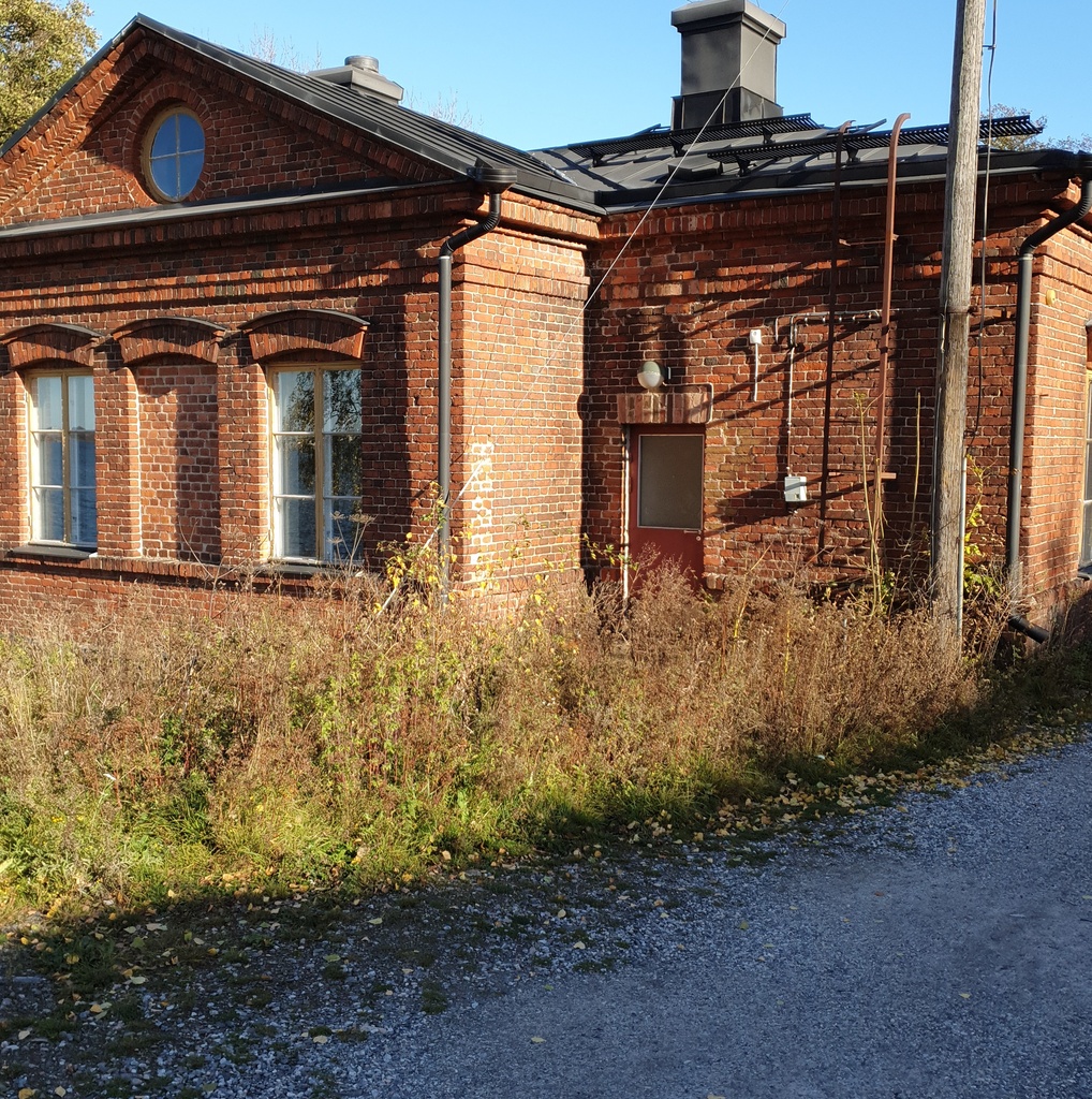 Vallisaarelaisia saaren luotsitalon pihapiirissä. Kaksi miehistä on sotilasunivormussa. Toisella naisista on sylissään pieni lapsi. Taustalla näkyvä tiilirakennus on luotsitalon sauna- ja pyykkitupa. rephoto