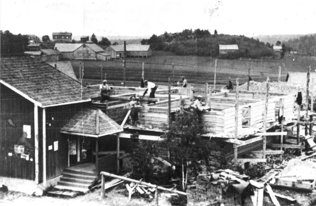 Kalle Helmisen kauppataloa rakennetaan, 1930-luku. (myöh. Koto-Asuste ja Koto-Kenkä). Etualalla liikerakennus rakenteilla. Taustalla näkyy peltoa ja Gunnarin taloa. Mäen päällä Yli-Gunnari. Kuvan rakennusmiehistä tunnistettu mm. Vuoto(?), Toivo Jokinen, Niemi. 

nm_vk_0676