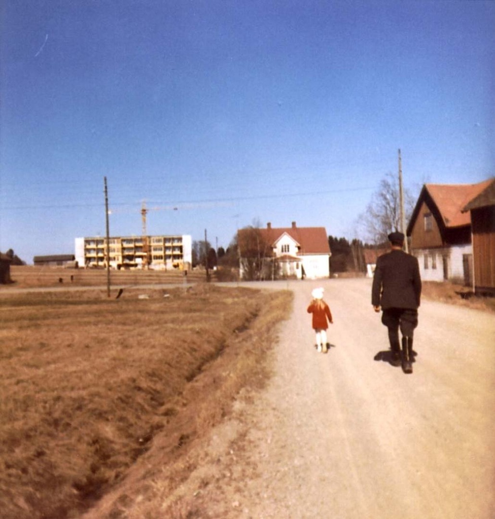 Klaukkalan kylän keskustaa, kevät 1969. Ensimäinen kerrostalo Kylä-Myllärin pellolle valmistuu. Kylänäkymää entiseltä Kuonomäentieltä. Jalmari Lilja tulossa Helena-kuopuksensa kanssa Eklundin mamman syntymäpäiväkahveilta. Kuvassa vasemmalta lukien Kylä-Myllärin navetan päätyä ja Gunnarin Alitalon lato, rakenteilla oleva kerrostalo, Kylä-Myllärin päärakennus ja työväenrakennus ja sauna. Kuonomäentien ja Klaukkalantien kulmassa Ali-Klaukan karjarakennuksia.

https://finna.fi/Record/nurmijarvi_mui.mui-33850