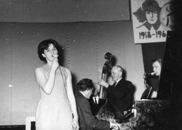 Tartu Raudteelaste Klubi isetegevusring: esineb solist Ljudmila Šutajeva estraadiansambli saatel.  Seinal plakat, peal punaarmeelase ja kosmonaudi portree.  Tartu, 1968.