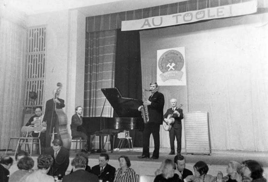 Tartu Raudteelaste Klubi isetegevusring: peoõhtul esineb estraadiansambel (akordion, kontrabass, klaver, kitarr, saksofon). Klaveril Nikolai Romanov. Seinal NSV Liidu vapp ja loosung "Au tööle!" Tartu, 3.03.1970.