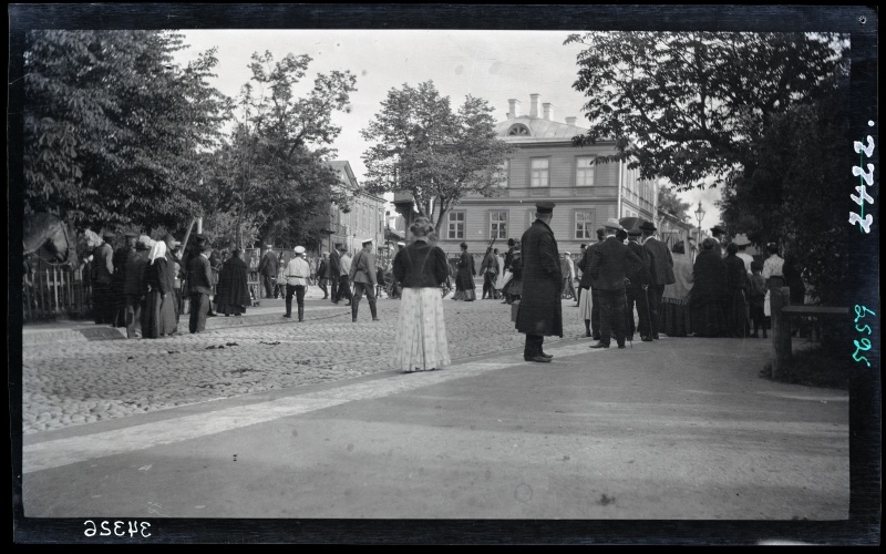 Marching soldiers and private people on the city street.