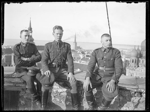 Three military personnel against the backdrop of the towers in Tallinn and the Russian Church