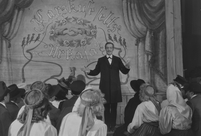 Kosjasõit, Teater Estonia, 1947, pildil: stseen etendusest, 1. vaatus, Karskusseltsi pidu, koori juhatab Kooli-Jaan – Arnold Ernesaks