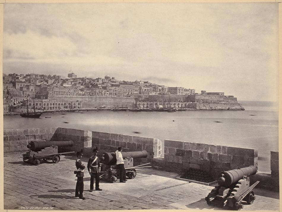 Francis Frith, Elmo Malta (No. 1969) - Francis Frith, Fort Saint Elmo, Valletta, Malta (No. 1969)
The soldiers are likely of the Royal Malta Fencible Regiment, who manned guns in lieu of the Royal Artillery and is of the 1860s or else they were visiting infantrymen and the gunner is dressed in the white jacket.