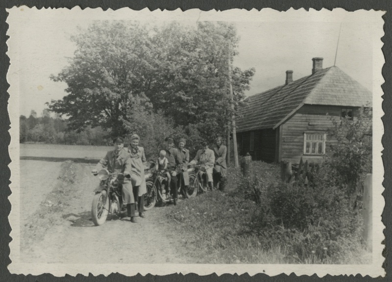 Three motorcycles with passengers along the road against the background of the building. First on the left - Valter and Ella Toomsalu.