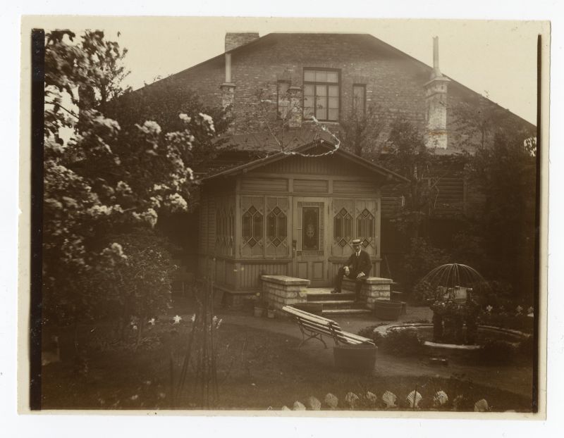 View of the building and garden with veranda. A man with a cable on the stairs. Garden floating.