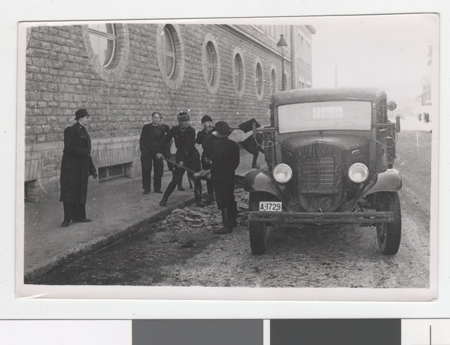 Members of I team cleaning the street from the snow in front of the fire extinguishing building