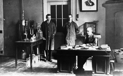Tartu ülikooli anorgaanilise keemia juhataja laboratooriumis, laua taga istub labori juhataja P. Kogerman, seisavad vasakul assistent H. Raudsepp, paremal assistent I. Põllumann, 1932.a.  duplicate photo