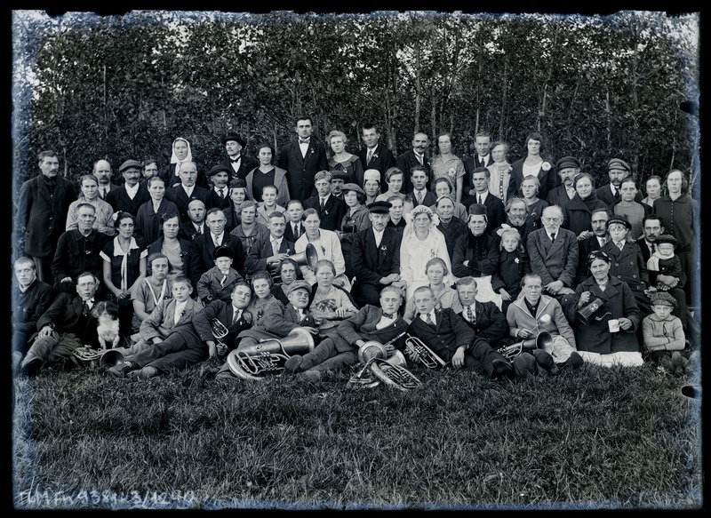 Grupiportree. Tundmatu pruutpaar  pulmakülalistega aias poseerimas.