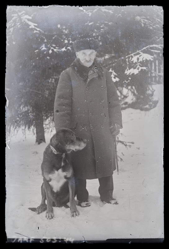 Vanema mehe täisfiguurportree talveriietes, koeraga