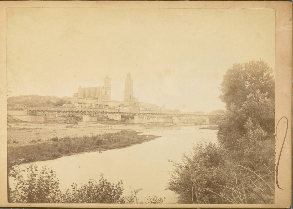 [View of the Onyar River] - View of the Onyar River at the height of the Railway Bridge with the Old Quarter in the background Under the bridge, on the left, the Galligants River aquaduct and next to it, the Barca portal. On the right, the footbridge Portal de la Barca. In the background stand the Cathedral of Girona and the bell church of Sant Feliu.