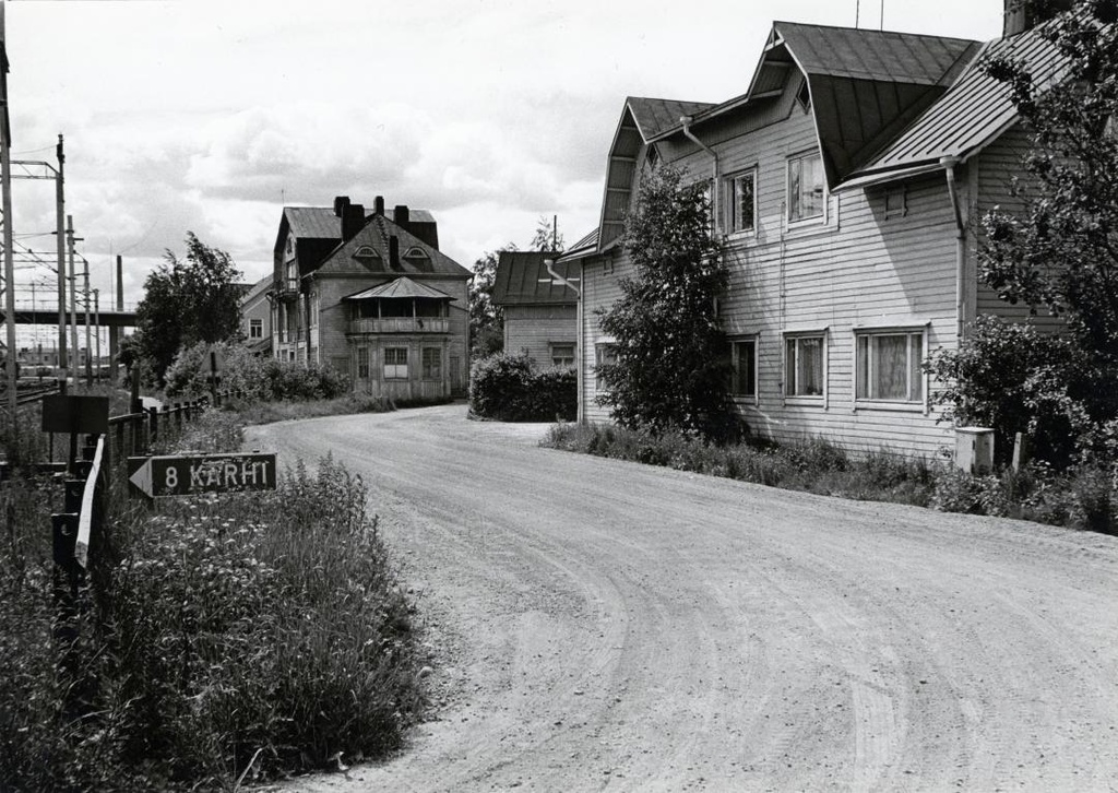 Pohjoinen rautatienkatu puu-Suokylässä vuonna 1974. Kuvassa oikealla Jussilan ja Ollilan talot sekä Hakkolan matkailijakoti edessä tien mutkassa. Kuva: Riihimäen kaupunginmuseo