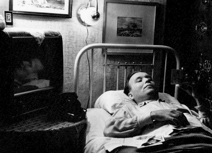 Foto: Paul Kamm halvatuna vanematekodus, laual teler, telefon, seinal põleb lamp.
