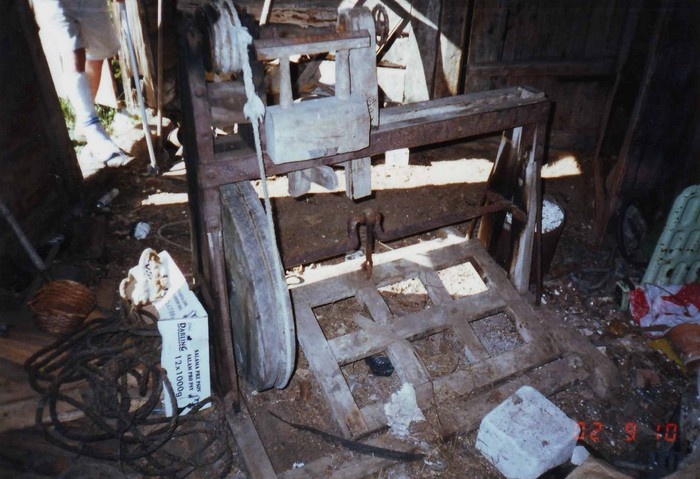 Kõpu küla Sepa talu sepikoja sisevaade, suures plaanis puutreipink, taga vasakul avatud ukseaugus inimese jalad.