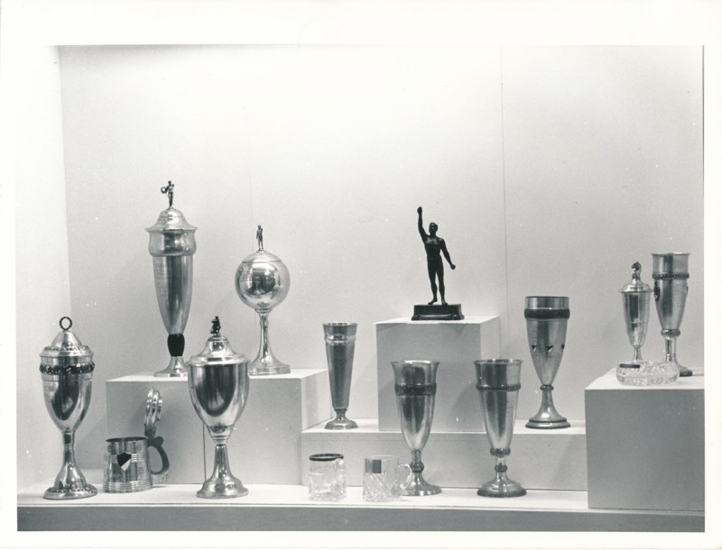 Üliõpilasorganisatsioonide näitus Tartu Linnamuuseumis 1989a. HHõbekarikad, -kannud, -peekrid, 2 klaaskannu, mehe figuur alusel.